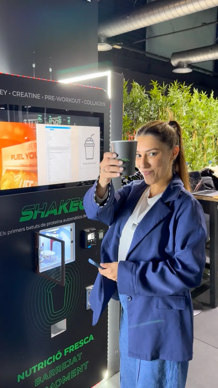Woman with SHAKEO cup at gym vending machine